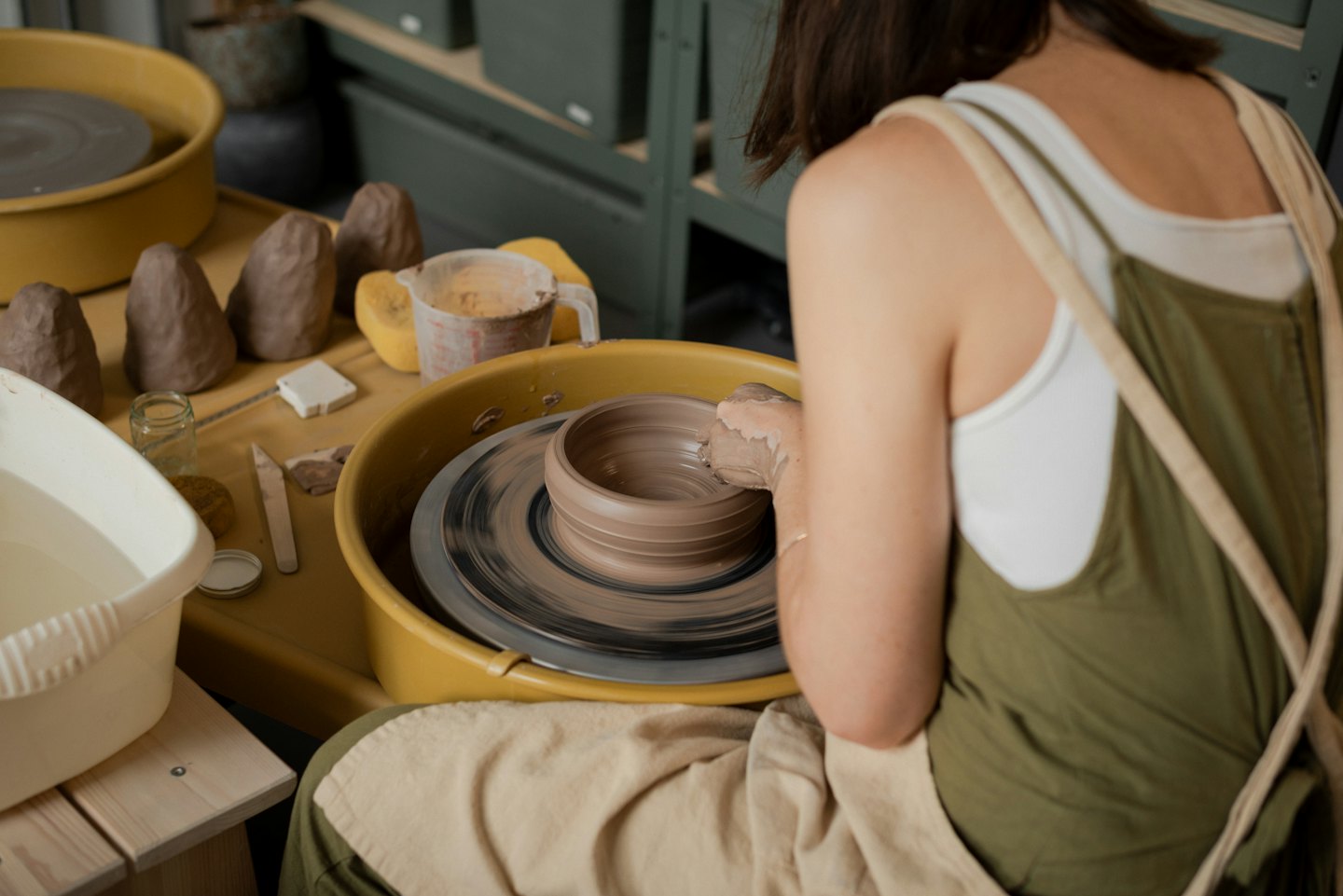 Frau formt eine Tonschale auf einer Töpferscheibe im Atelier.